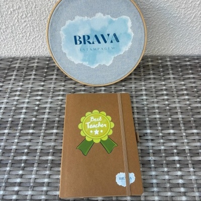 Bloco de notas com insígnia Best Teacher e bastidor de tecido com texto BRAVA ESTAMPAGEM