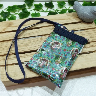 Bolsa pequena colorida com estampa de Frida Kahlo e fecho de zíper azul sobre base de madeira