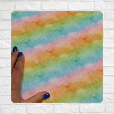 Tecido multicolorido em tons pastel com padrão de riscas diagonais e mão com unhas azuis