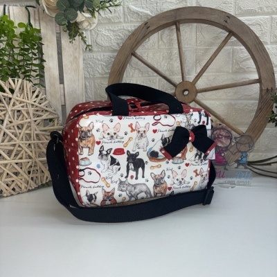 Bolsa estampada com bulldogs franceses, fundo com bolinhas vermelhas, alças pretas e laço, sobre superfície branca com decoração ao fundo