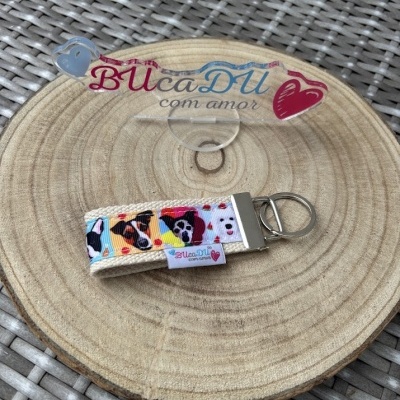 Chaveiro com padrão de rostos de cães e acabamento metálico sobre base redonda de madeira clara