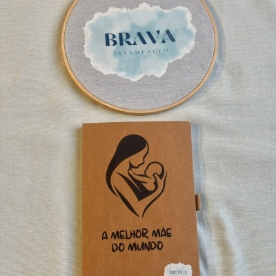 Caderno castanho com ilustração de mãe e bebé e texto em português, marca Brava Estampagem