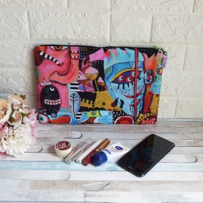 Necessaire colorida com padrão artístico, flores, cosméticos e telemóvel sobre superfície de madeira