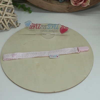 Bandolete rosa claro com bolinhas brancas sobre base redonda de madeira clara.