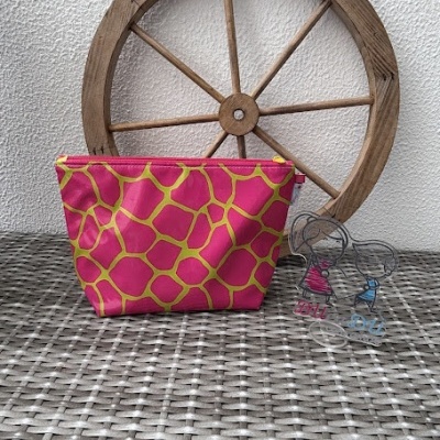 Bolsa rosa com padrão amarelo e roda de madeira ao fundo