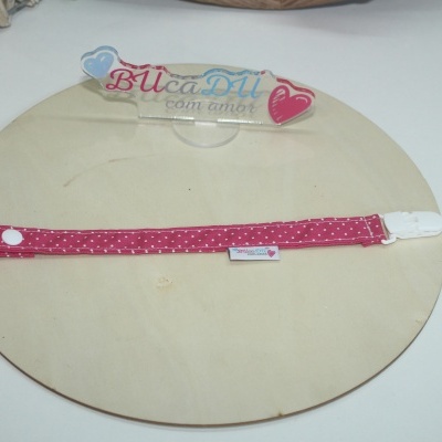 Fita vermelha com pontos brancos e clipe branco em base redonda de madeira com placa com texto