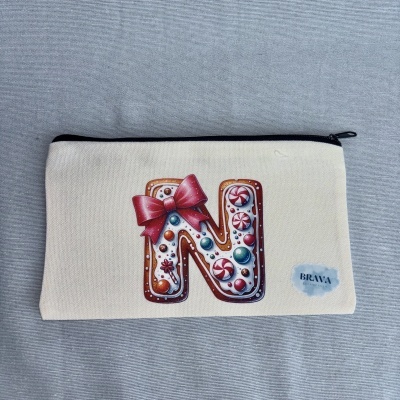 Estojo bege com fecho preto e letra N decorada com biscoito e balas coloridas
