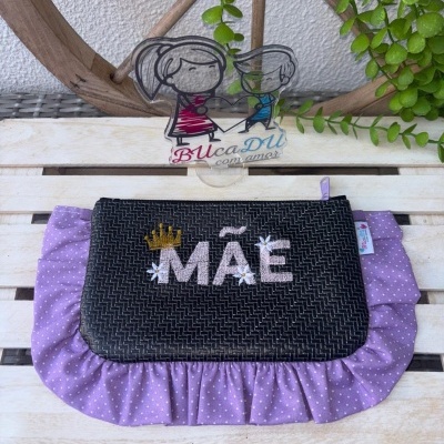Carteira com bordado MAÊ e tecido lilás com bolinhas sobre superfície de madeira clara