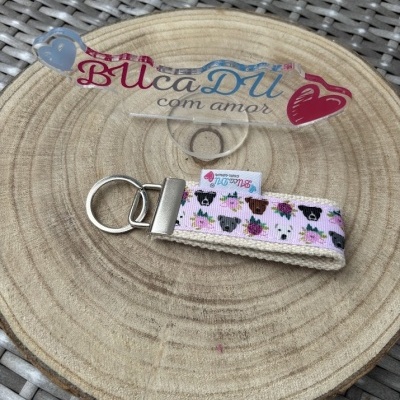 Porta-chaves em tecido com padrão de cães e flores sobre madeira redonda