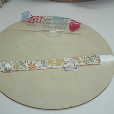Tira de tecido floral com clip branco sobre suporte circular de madeira