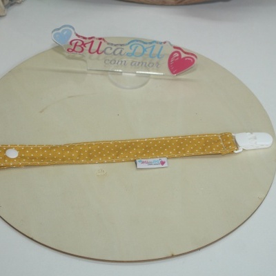 Fita amarela com pontos brancos e clip branco sobre madeira clara com texto BUcaDU com amor