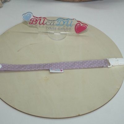 Fita lila com bolinhas brancas e fecho plástico sobre placa de madeira com placa acrílica BUcaDU com amor