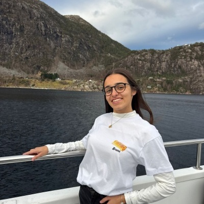 Mulher com t-shirt branca estampada com nome Bruna num cenário de rio e montanhas