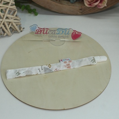 Fita com padrão colorido sobre base de madeira e objeto de vime com flores ao lado