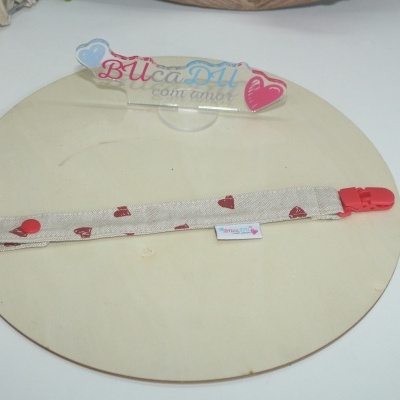 Prendedor de tecido com coração e clip vermelho sobre base de madeira redonda