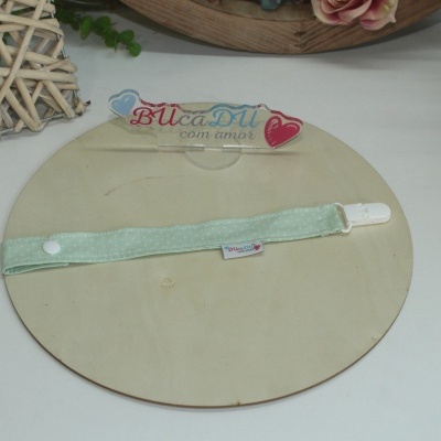 Fita verde claro com botão e clipe branco sobre suporte de madeira com placa acrílica com texto