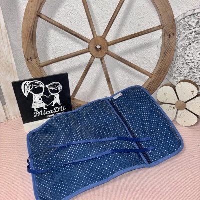 Estojo azul com bolinhas brancas e fecho, junto a roda de madeira e decoração.