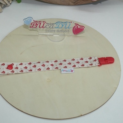 Correia de tecido branco com padrão de flores vermelhas e clip vermelho sobre placa de madeira clara