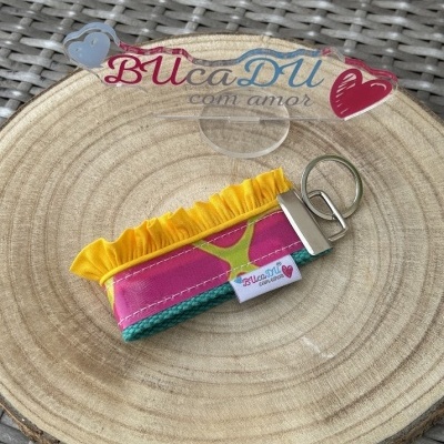Chaveiro colorido em tecido com argola metálica sobre placa de madeira