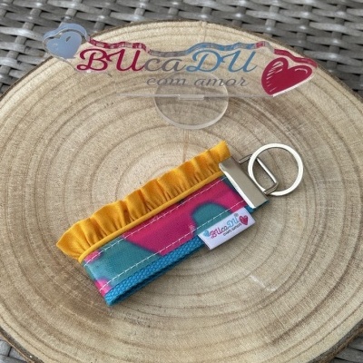 Chaveiro colorido de tecido com corações e etiqueta BUcaDÚ com amor sobre tabuleiro de madeira
