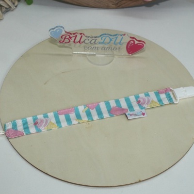 Tira de tecido com padrão de raias azuis e desenhos de gelados cor-de-rosa com fecho branco