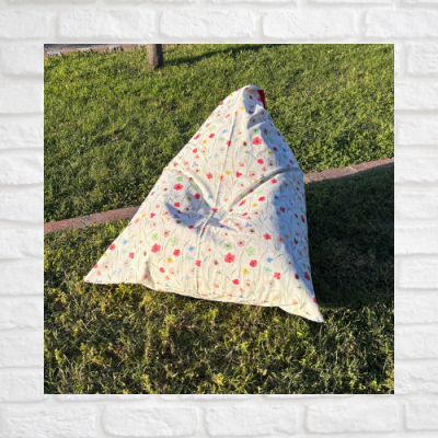 Pufe almofadado com padrão floral sobre relva