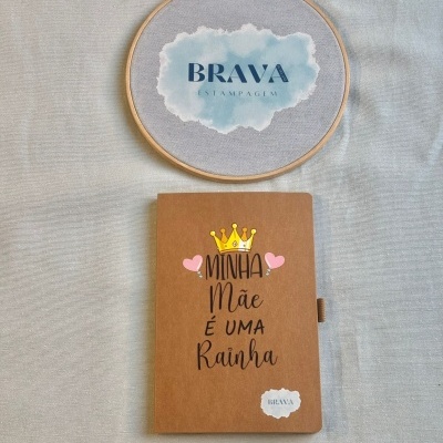 Caderno castanho com texto decorativo e bastidor de bordado com logotipo BRAVA