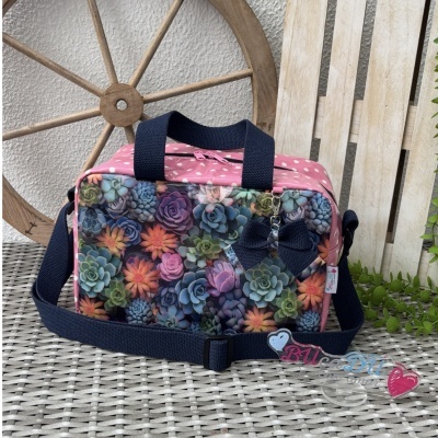 Mala com padrão de plantas coloridas, corpo rosa com bolinhas brancas e alças azuis escuras