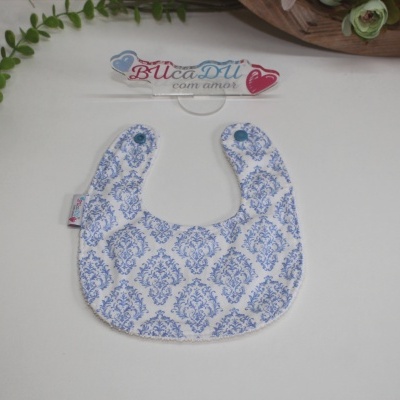 Babete para bebé branco com padrão azul e botão de pressão azul