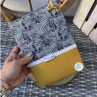 Capa com padrão zebras preto e branco e parte inferior amarela com bolinhas brancas e laço amarelo.