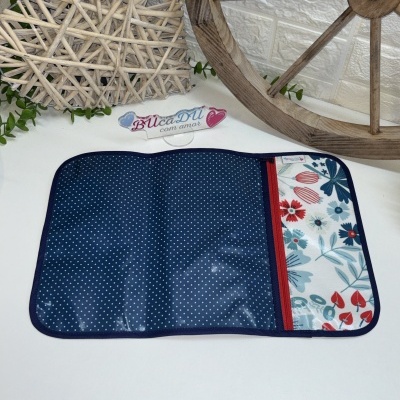 Estojo aberto com padrão azul às bolinhas e padrão floral colorido com fecho vermelho