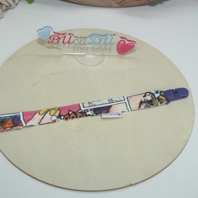 Clip para roupa de bebé colorido com padrão de banda desenhada e fecho roxo numa base de madeira