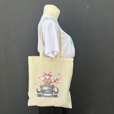 Mala de tecido bege com ilustração de senhora a conduzir carro clássico azul.