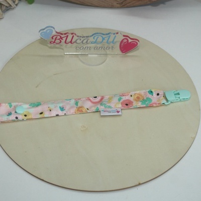 Suporte para chucha floral com clip azul claro sobre base de madeira