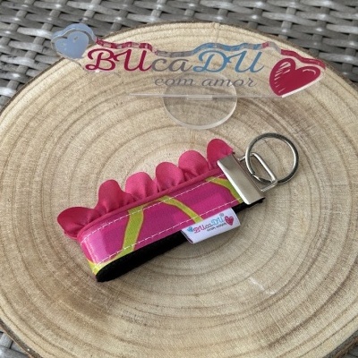 Chaveiro colorido em tecido com argola metálica sobre base de madeira e vime