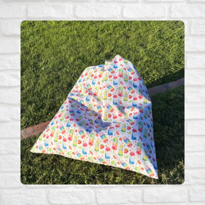 Pufe triangular com padrão de gelados e frutas ao ar livre sobre relva