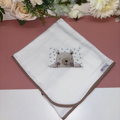 Fralda branca bordada com ursinho e bolinhas azuis em fundo rosa e branco com flores