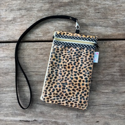 Carteira animal print com alça preta sobre madeira