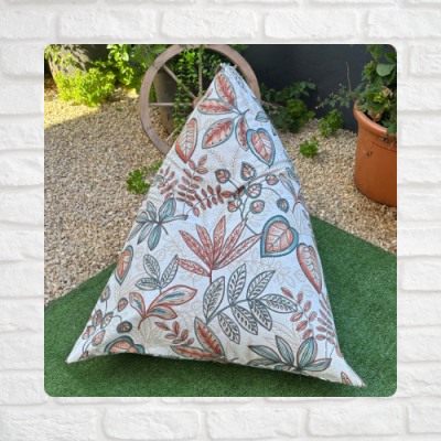 Puff triangular com estampa de folhas coloridas em ambiente exterior.