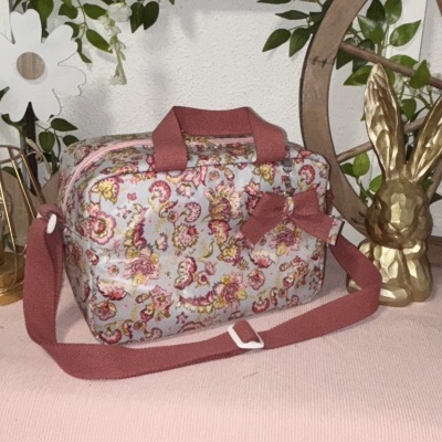 Bolsa floral com alças rosa antigo sobre mesa rosa com decoração
