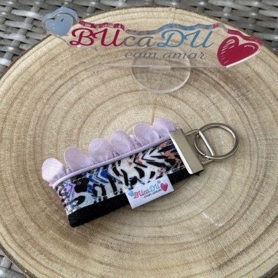 Chaveiro com padrão animal print e detalhes lilás sobre disco de madeira