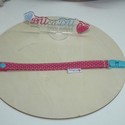 Tira vermelha com pontos brancos e fecho azul em placa de madeira clara