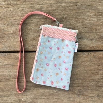 Bolsa pequena com padrão floral e alça rosa sobre madeira