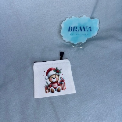 Bolsa branca com estampa de ursinho natalino e placa acrílica azul com texto BRAVA ESTAMPAGEM