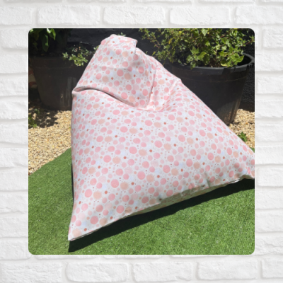 Pufe triangular rosa e branco com padrão de círculos em ambiente exterior