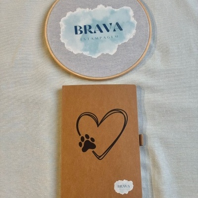 Caderno castanho com coração e pata preta e aro de bordado com texto BRAVA ESTAMPAGEM