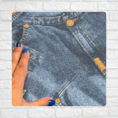 Calça de ganga azul com botões dourados e mão com unhas azuis