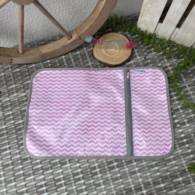 Tapete ou toalha rosa e branco com padrão zig-zag em superfície de vime cinzento