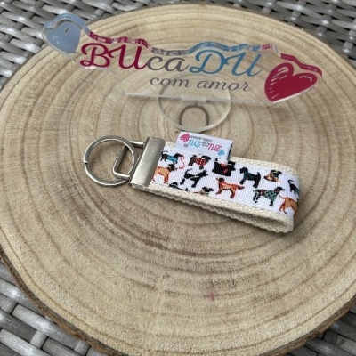 Porta-chaves bege com fita branca estampada com cães e placa acrílica com texto BUcaDU com amor