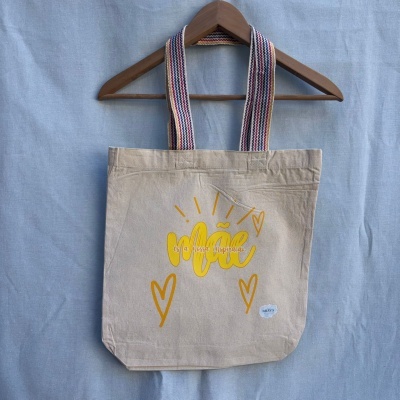 Saco de tecido bege com alças listradas e estampa amarela com texto e corações